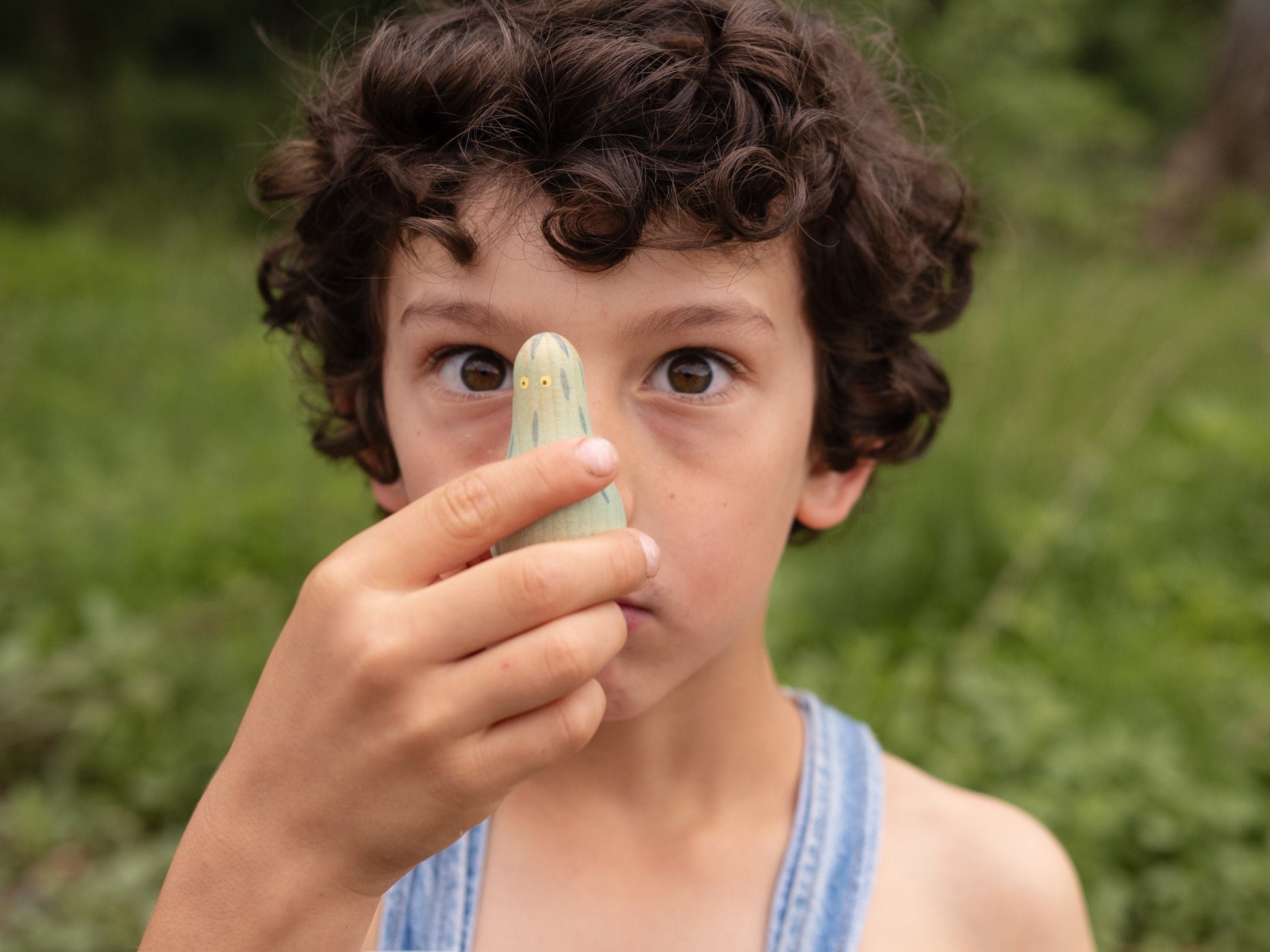 Child holding a small object to their nose outdoors