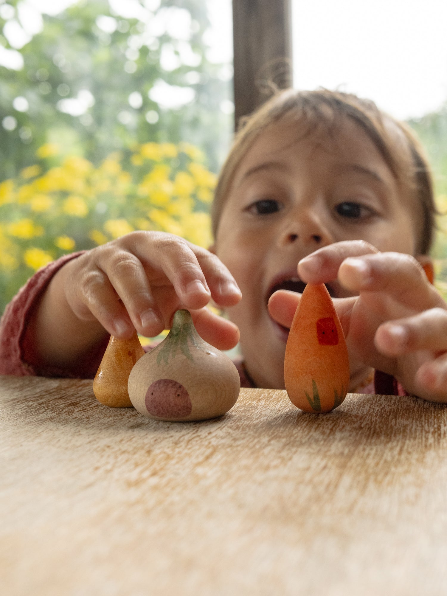 Child playing with small vegetables on a table outdoors