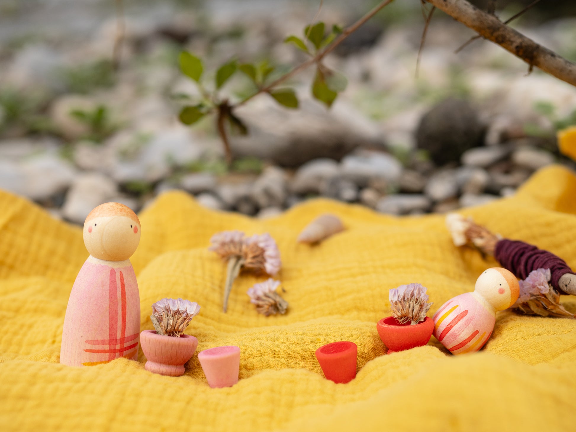 Small figurines and plants on a yellow fabric with a natural background