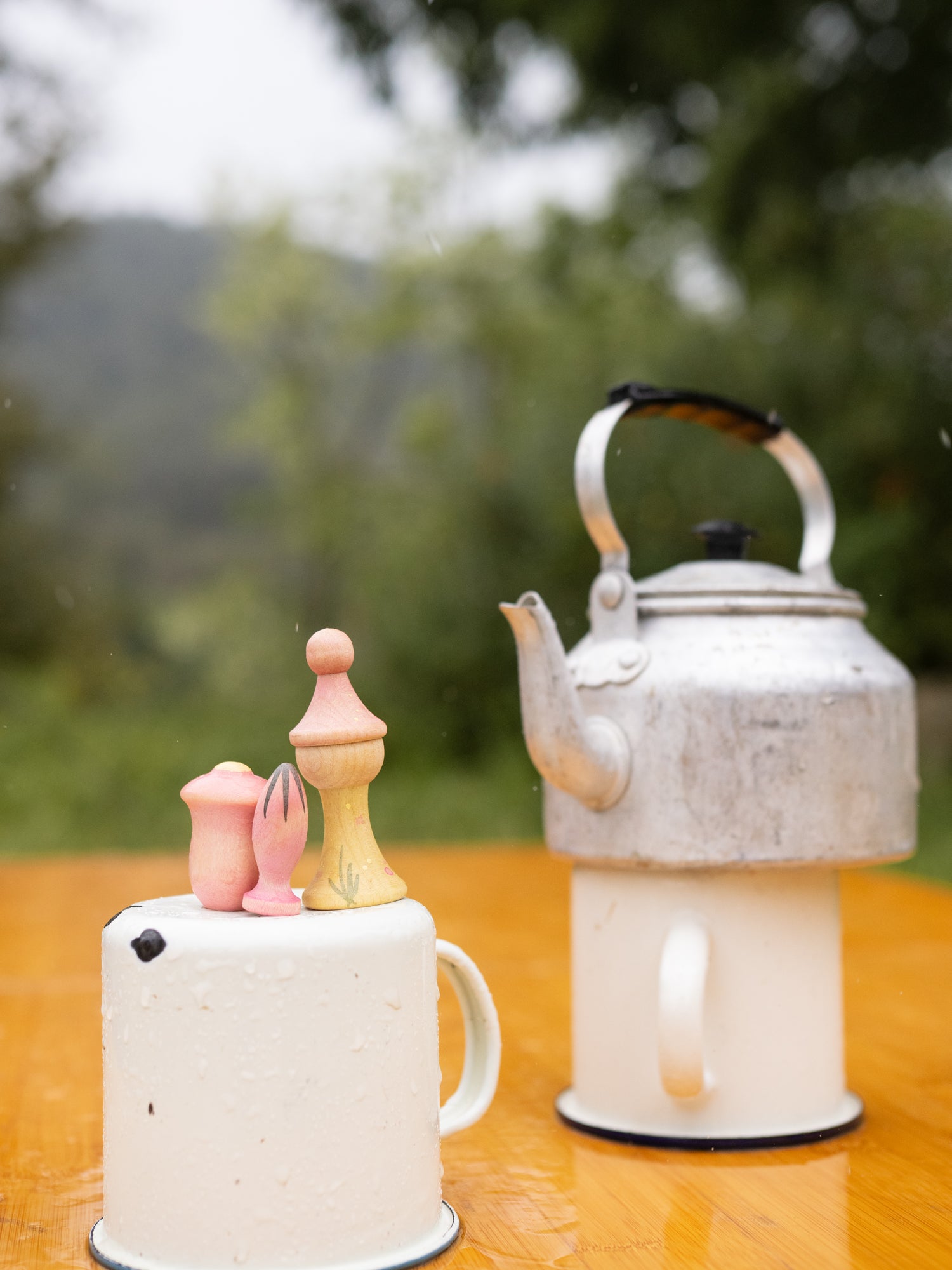 Decorative teapot and candle on a wooden surface with a blurred natural background