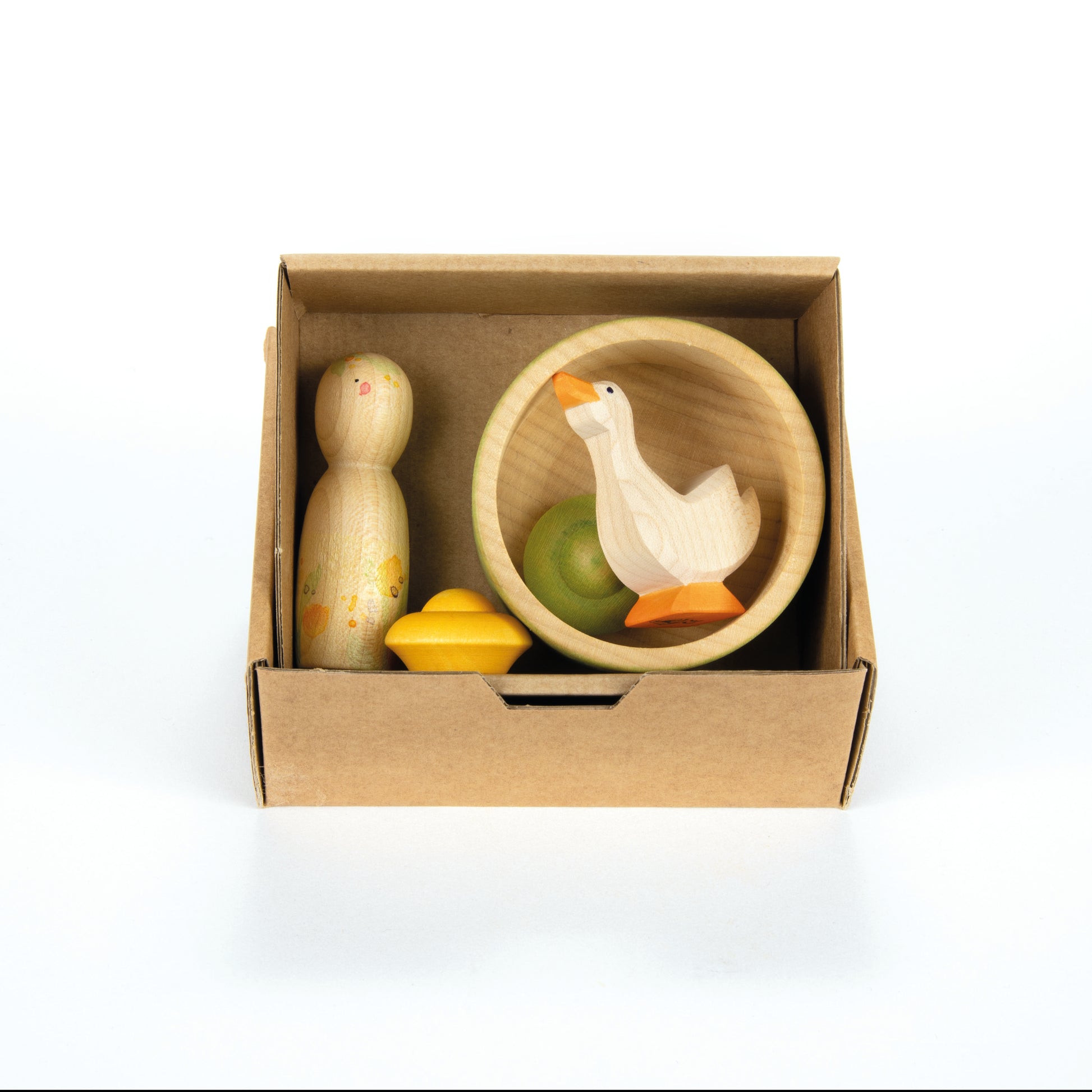 Set of wooden toys including a goose, duck, and green ball in a cardboard box on a white background.