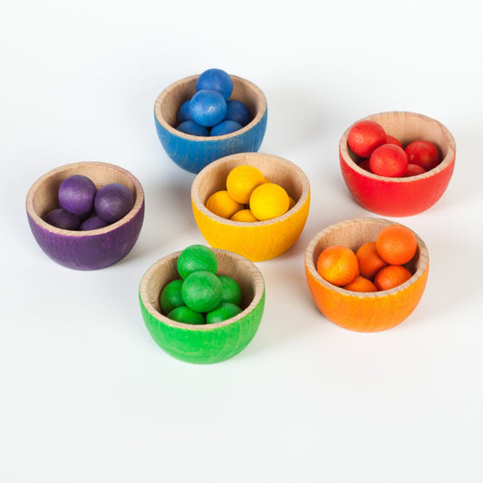 Set of colorful wooden toy bowls with small colourful wooden balls on a white background
