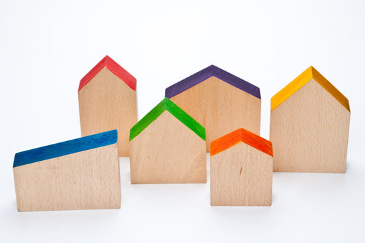 A set of wooden toy houses in various shapes with brightly coloured roofs