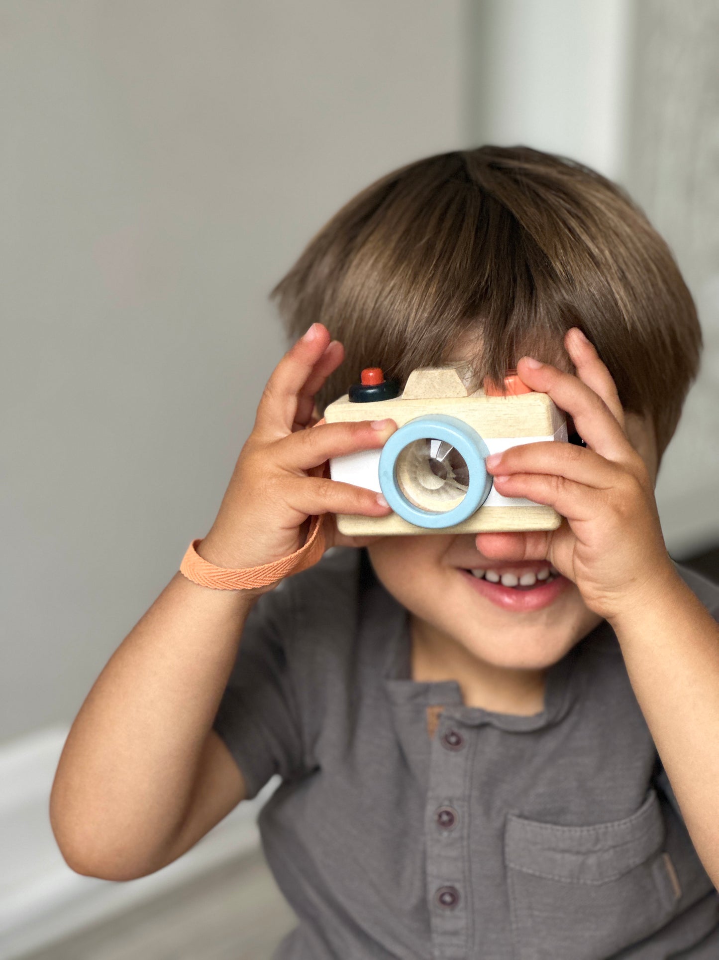 Child playing with wooden camera