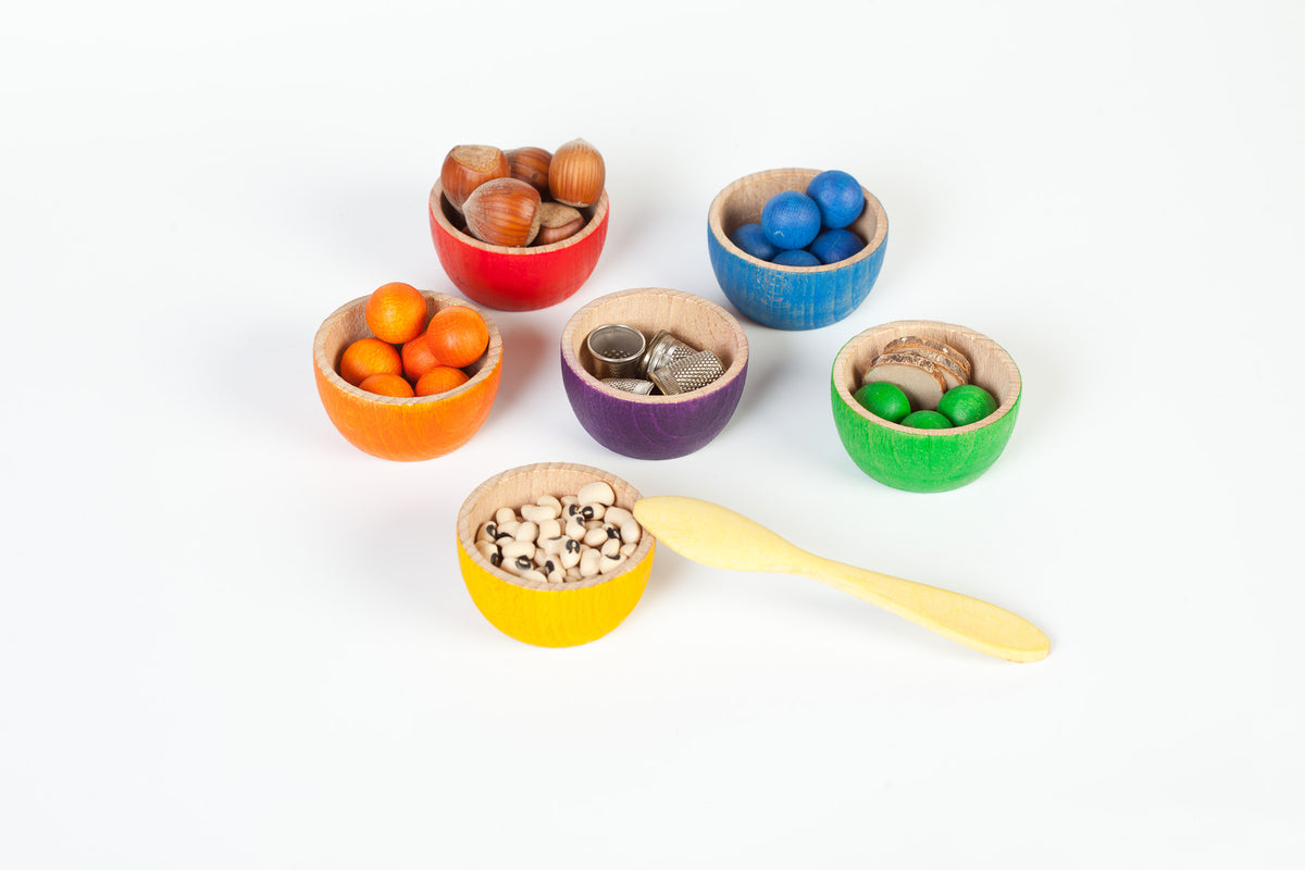 Colourful wooden toy bowls filled with colourful marbles and other natural materials
