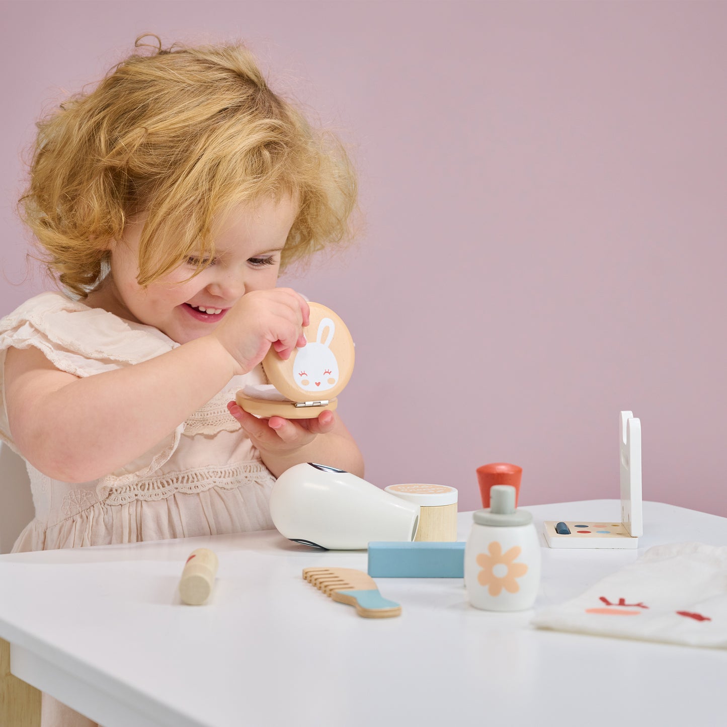 Child playing with wooden toy bunny themed make up set.  Looking in mirror.