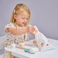 Child playing with wooden toy bunny themed make up set.  Looking in fabric bag.