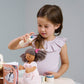 Child playing with wooden pretend play hair salon.  Spraying doll's hair.  