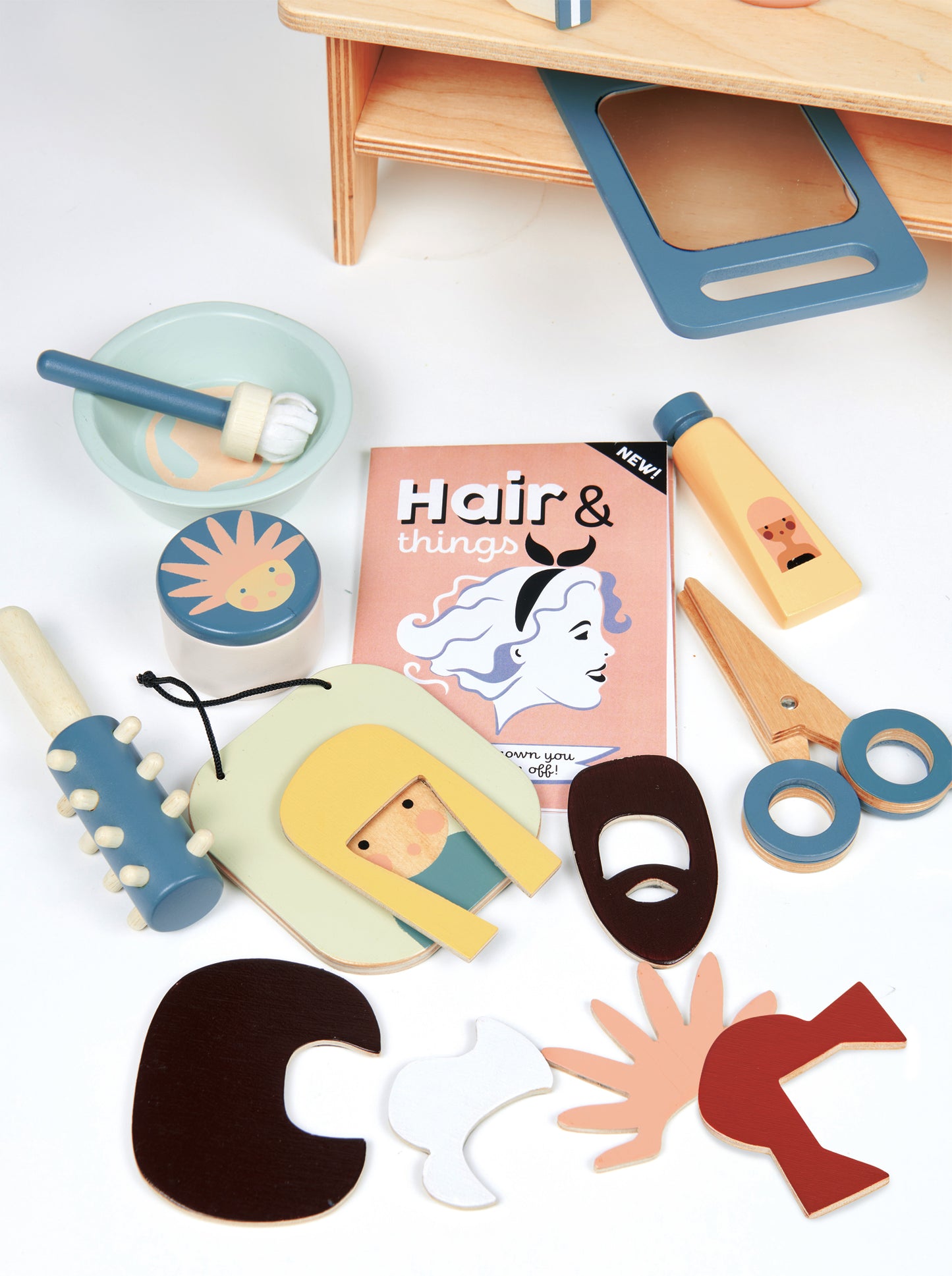 Wooden pretend play hair salon accessories including brushes, shampoo, scissors, magazine and magnetic face with different hair styles.