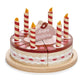 Wooden toy chocolate birthday cake with six candles and cake topper which says happy birthday.  The cake is divided into six pieces and presented on a wooden plate.
