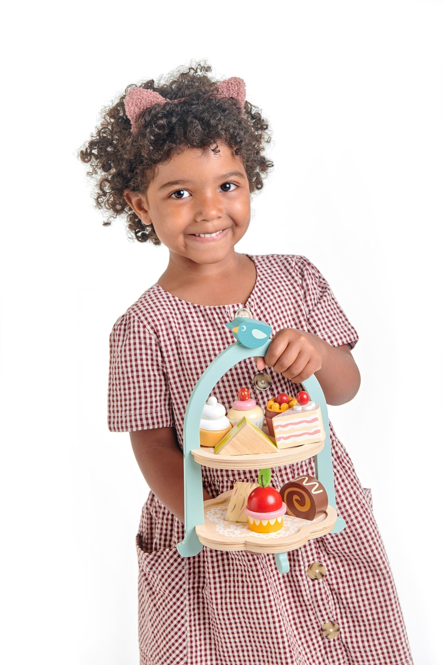 Child holding wooden toy afternoon tea set