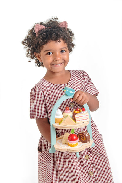 Child holding wooden toy afternoon tea set